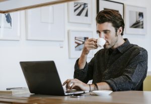 orang kerja dengan laptop sambil minum kopi